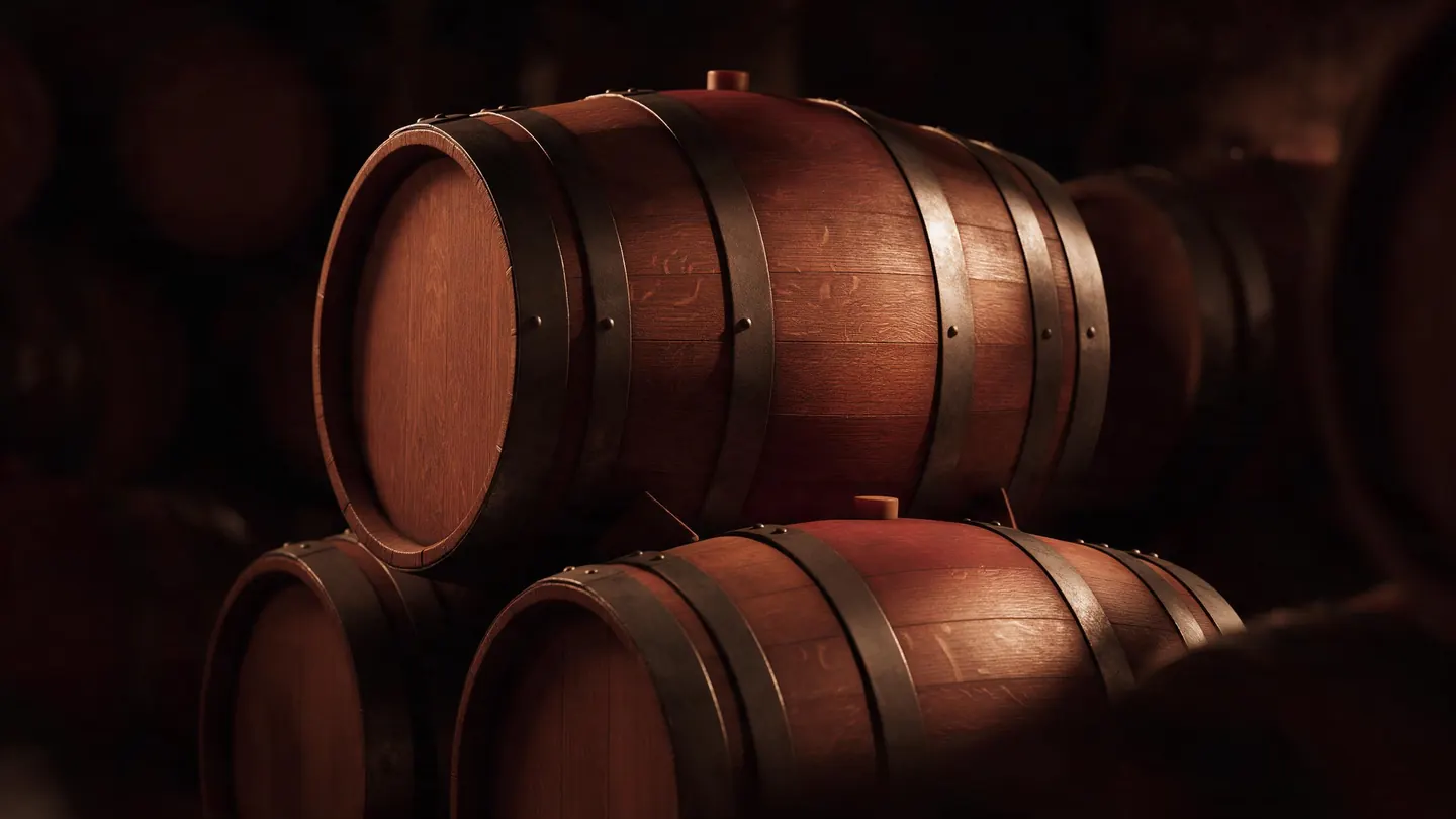 Barricas de roble apiladas en la penumbra de la bodega